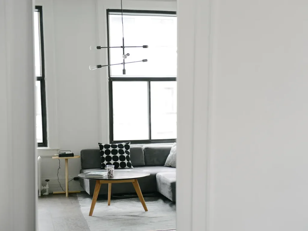 Bright minimal living room with a grey sofa, round coffee table and tall window